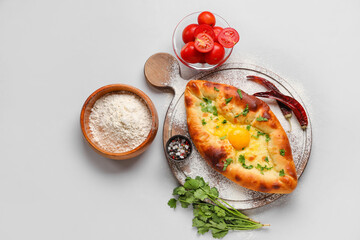 Composition with tasty Ajarian khachapuri, flour and tomatoes on white background