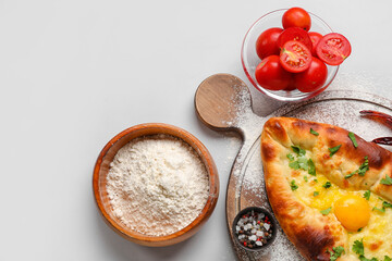 Composition with tasty Ajarian khachapuri, flour and tomatoes on white background
