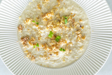 Delicious and creamy risotto dressed with cheese and walnuts on white plate. Top view and close up