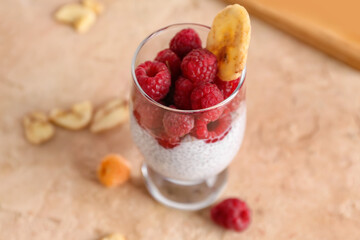 Glass with delicious chia seed pudding and ripe raspberry on color background