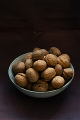 Bowl full of walnuts on black background with copy space