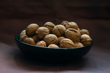 Bowl full of walnuts on black background with copy space