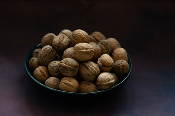 Bowl full of walnuts on black background with copy space