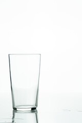 Empty glass tumbler with traces of water on the surface on a white background