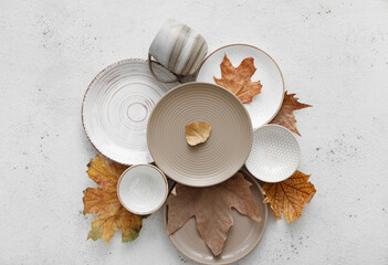Fototapeta na wymiar Beautiful plates with cup and autumn leaves on white background
