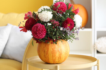 Pumpkin with beautiful flowers on table in living room, closeup