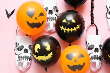 Funny Halloween balloons and paper lanterns on pink background