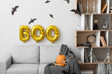 Interior of living room decorated for Halloween with balloons, sofa and shelving unit