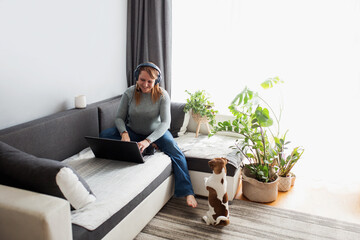 A young woman is working at home on the computer. Working at home with a computer and headphones.