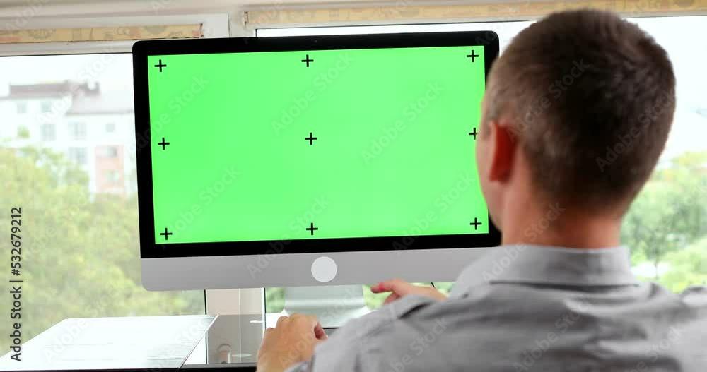 Poster green screen. employee working at computer sitting at desk. view from back.