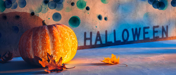 Halloween holiday pumpkin on concrete stone floor with autumn leaves and dark dirty spooky bokeh