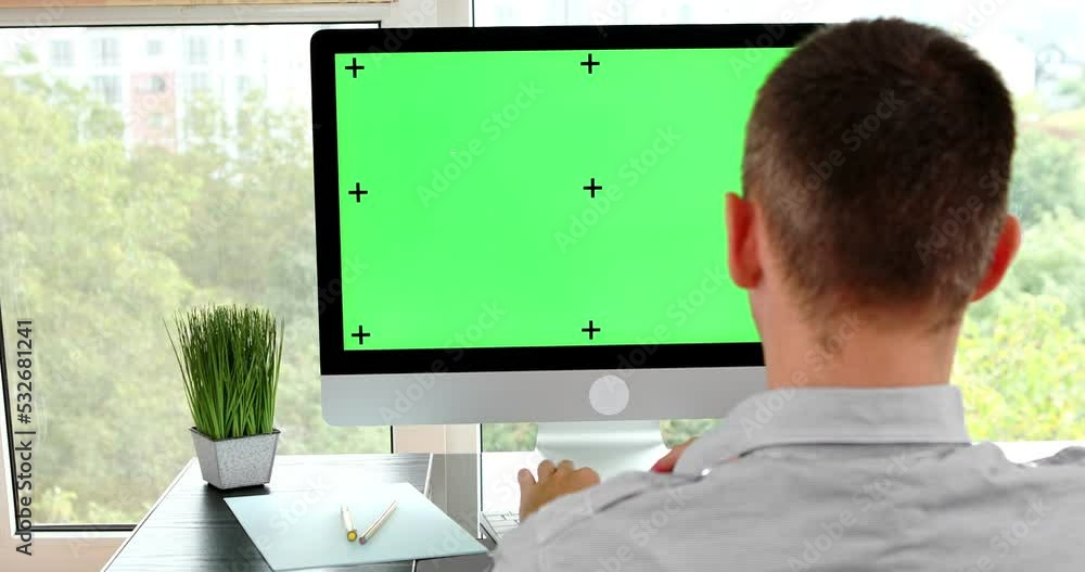 Poster green screen. employee working at computer sitting at desk. view from back.