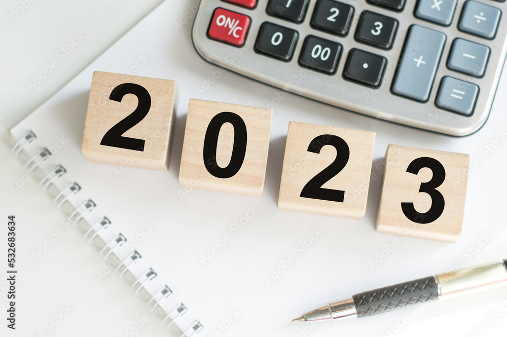 Poster 2023 text on wooden cubes on a table on the background of a notebook, a calculator