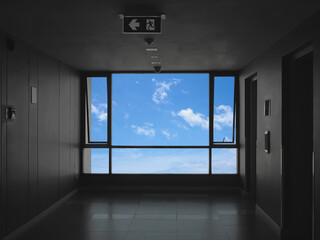 Glass window over blue sky background at hallway in front of lifts in condominium.