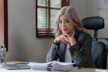 Beautiful Asian businesswoman analyzes financial charts. Account and audit concept