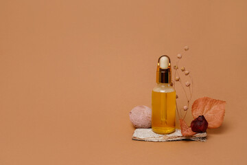 Glass cosmetic bottle with oil and autumn composition on orange background, copy space. autumn skin...