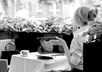 Black and white photo banner with a business woman talking on an iphone in a summer cafe. View from...