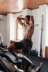 Fototapeta premium Shirtless young black man doing intense cardio workout on exercise bike at the gym