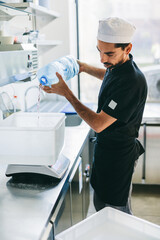 Obraz premium Italian chef pizzaiolo preparing pizza dough in restaurant kitchen