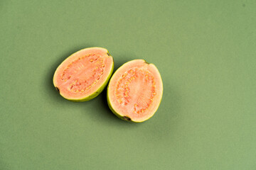 The common guava Psidium guajava (lemon guava, apple guava) on green olive color background. Close up view.