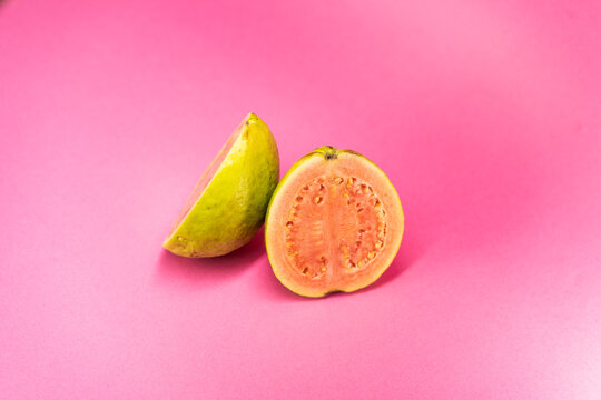 The common guava Psidium guajava (lemon guava, apple guava) on rose color background. Close up view.