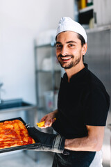 Italian chef pizzaiolo putting pizza to oven in restaurant kitchen