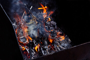 Burning red hot sparks fly from fire. Barbecue gril with glowing and flaming hot charcoal and firewood