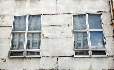The old concrete wall with windows. Abandoned  facade of factory or industrial building