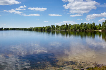 Beautiful river landscape. Lake surface on a sunny perfect day. The surface of the water against the background of trees and a blue sky. Blurred image, selective focus