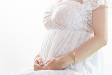 マタニティドレスでお腹に手をそえる妊婦 白背景（本物の臨月妊婦さんを撮影）