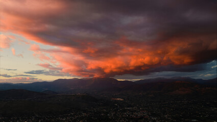 View from above, stunning aerial view of a dramatic sunset with beautiful clouds over a mountain range.