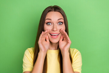 Portrait of ecstatic unbelievable unexpected girl straight hairdo wear yellow t-shirt hands on cheeks isolated on green color background