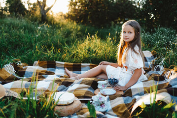 A girl in a white dress is having a picnic in the garden
