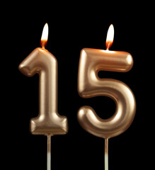 Burning gold birthday candles isolated on black background, number 15	
