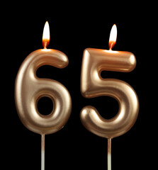 Burning gold birthday candles isolated on black background, number 65	