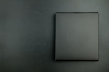 Empty black box on a black background. Top view at the studio. Small black box product packaging