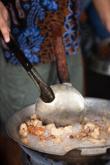 Close up a woman cooking of krenyos,  a popular traditional food from bantul yogyakarta. made from goat fat fried with garlic and salt. 