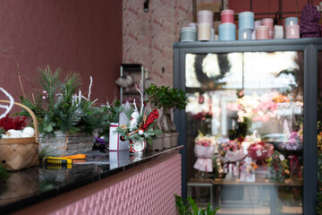 the interior of a stylish shop selling flowers with a Christmas tree arrangement made of natural pine needles on the counter in the foreground