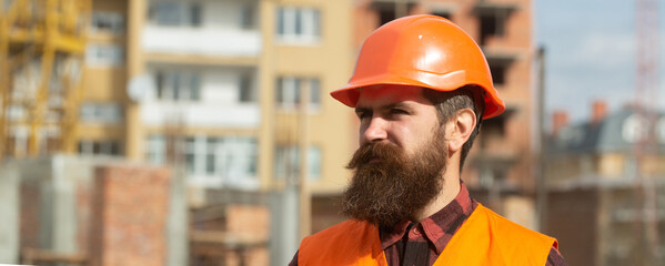 Man builder worker in helmet posing on construction site. Building and construction site concept.