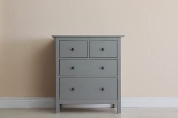 Grey chest of drawers near beige wall