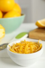 Grated lemon zest and fresh fruits on white wooden table, closeup