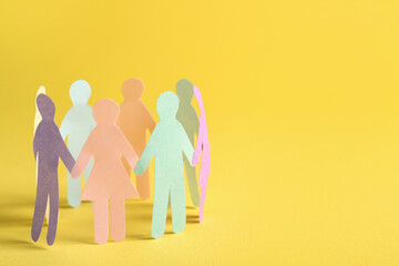 Many different paper human figures standing in circle on yellow background, space for text....
