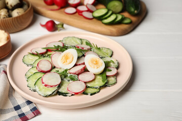 Tasty fresh salad with cucumber and ingredients on white wooden table