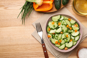 Tasty fresh salad with cucumber served on wooden table, flat lay. Space for text