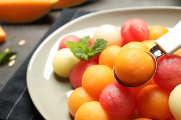 Melon and watermelon balls with scoop on plate, closeup