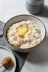 Unusual healthy delicious rice pudding made from brown rice and plant based milk served with butter and honey in grey bowl