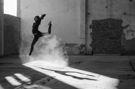 Ballerina dancing in an abandoned building on a sunny day in black and white