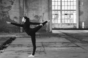 Fototapeta na wymiar Ballerina dancing in an abandoned building on a sunny day in black and white
