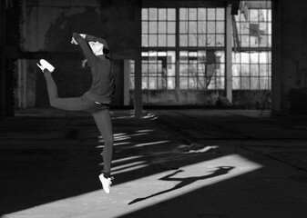 Ballerina dancing in an abandoned building on a sunny day in black and white