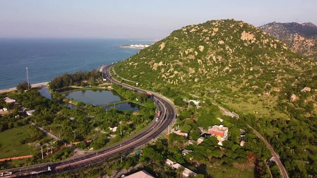 Backwards aerial view over a promontory next to main coastal road. Ca Na, Vietnam.